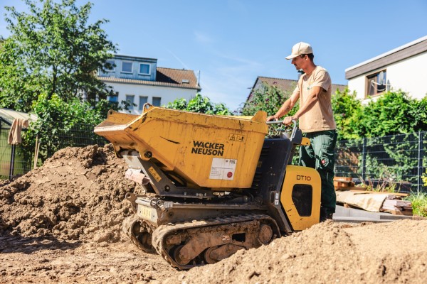 Ein Mitarbeiter, der ein Baustellenfahrzeug durch Berge von Erde fährt.